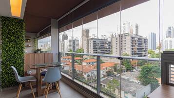 Uma varanda com vista para a cidade, uma mesa de jantar com cadeiras e uma parede verde.