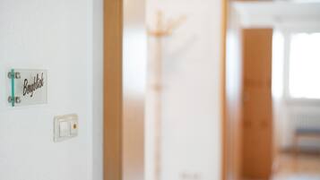 A sign with the word 'Bergblick' on a wall, a light switch, and a coat rack in the background.