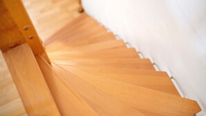 Una escalera de madera con una pared blanca a un lado.