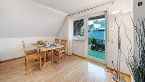 Un comedor con una mesa y sillas de madera, una ventana con cortinas y una lámpara de pie.