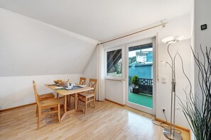 A dining area with a wooden table and chairs, a window with curtains, and a floor lamp.