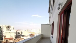 A balcony with a tiled floor, a red door, and a view of surrounding buildings. - Central/2 Bedrooms/KingBed/Balcony/FullKitchen (Durazzo)