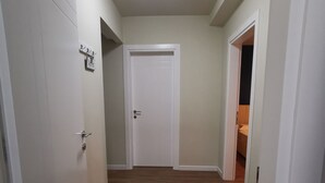 A hallway with wooden flooring, white walls, and a white door at the end. - Central/2 Bedrooms/KingBed/Balcony/FullKitchen (Durazzo)