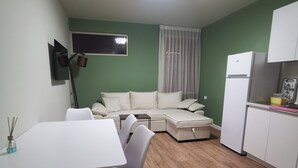 A compact living space with a dining area, a sofa bed, a kitchen area, and a window with curtains. - Central/2 Bedrooms/KingBed/Balcony/FullKitchen (Durazzo)