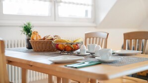 Una mesa de comedor con un frutero, pan y tazas.