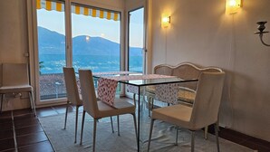 Un comedor con mesa y sillas, vistas a montañas y un balcón con barandilla.