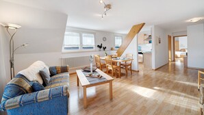 Una sala de estar moderna con sofá, mesa de comedor y zona de cocina.