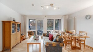 En rummelig stue med sofa, spisebord og et træskab.
