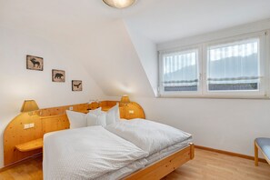 A bedroom with a wooden bed, a bench, a window with curtains, and three wall-mounted animal-themed pictures. - Holiday Apartment 'Waldblick' with Balcony and Wi-Fi (Biederbach)