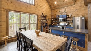 Cocina de cabaña de madera con una isla grande, mesa de comedor de madera y taburetes de bar.