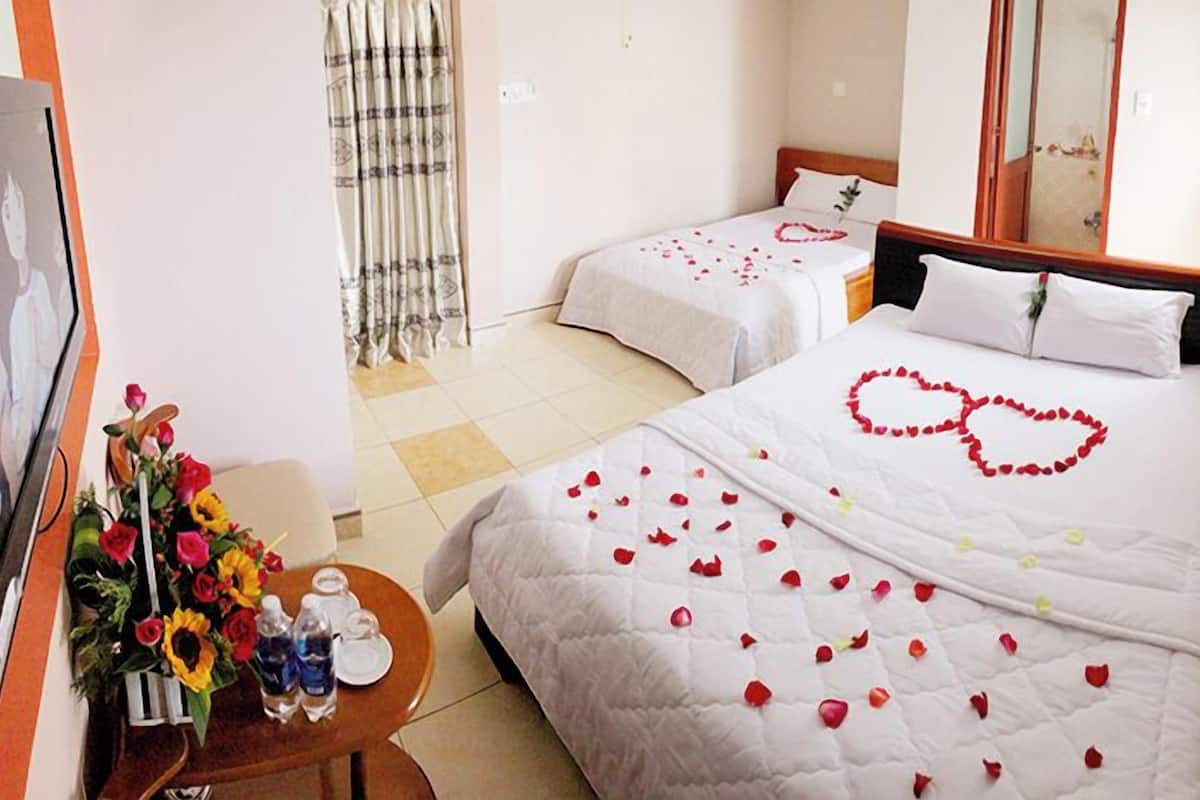 A hotel room with two beds, one with a heart-shaped decoration on the bedspread.