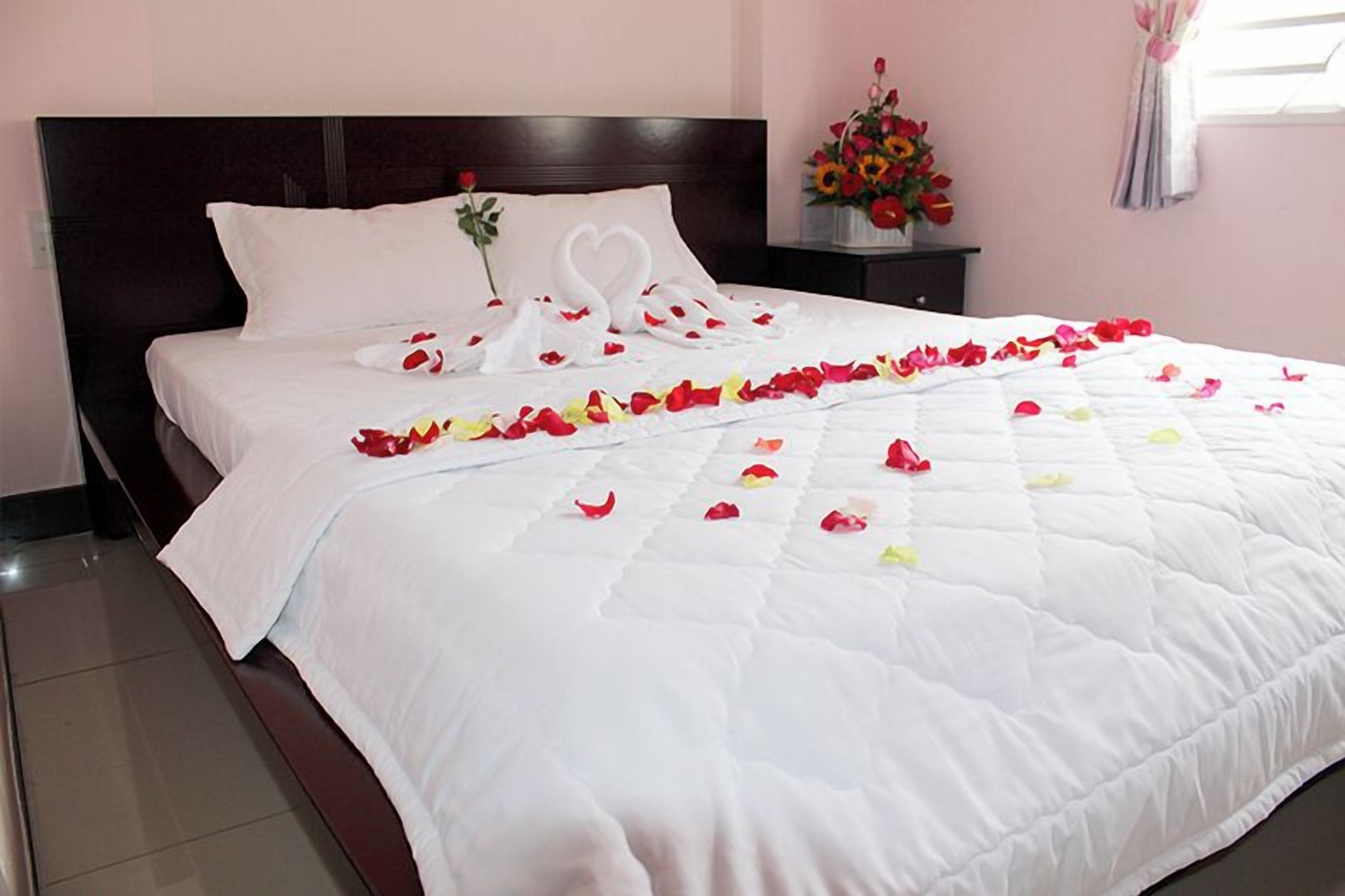 A neatly made bed with a white bedspread and a heart-shaped decoration on the pillow.