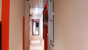 A corridor with a red accent wall, a door on the left, and a window on the right. - Ban Mai Hotel 66 (Phu Thuy)
