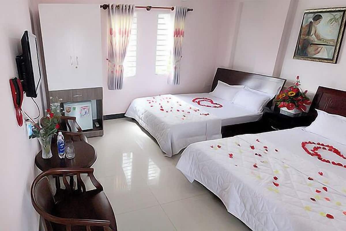 A hotel room with two beds, a desk, a chair, a TV, and a painting on the wall.