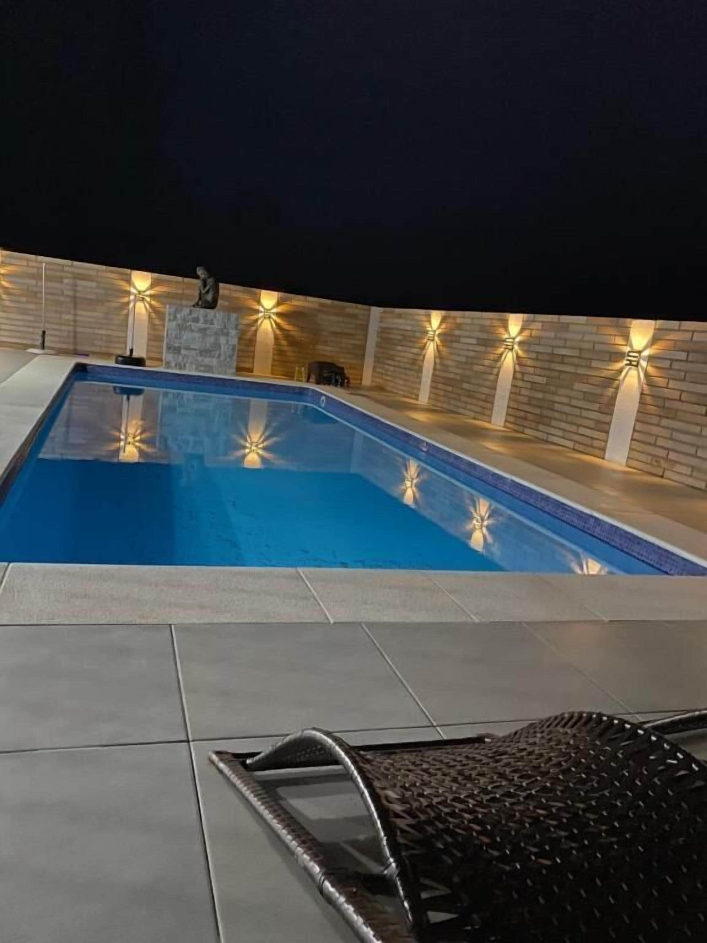 A swimming pool with a tiled deck and a black metal chair.
