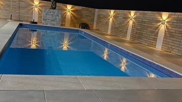 A swimming pool with a tiled deck and a black metal chair.