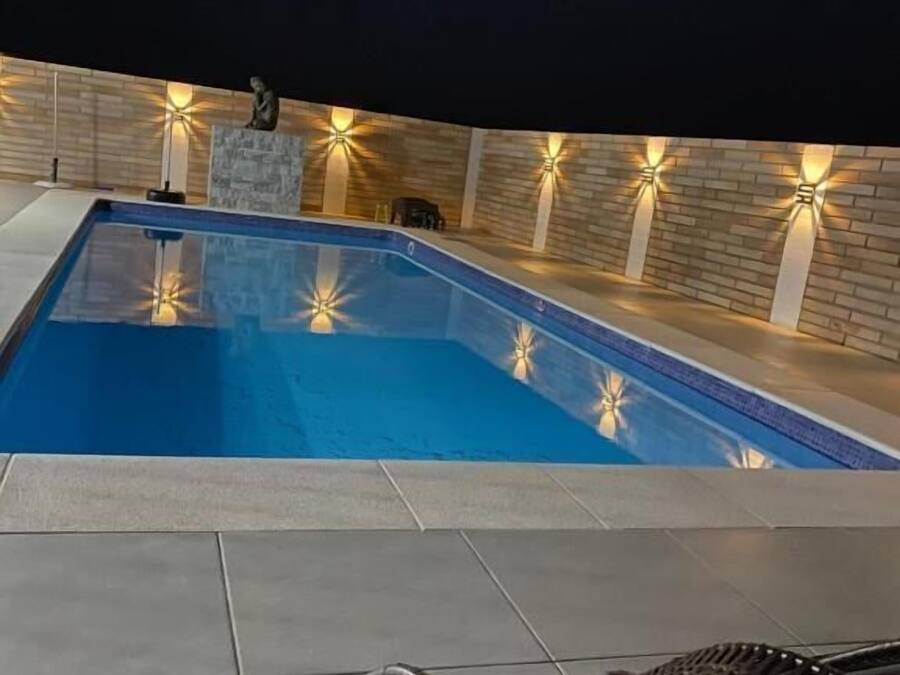 A swimming pool with a tiled deck and a black metal chair.
