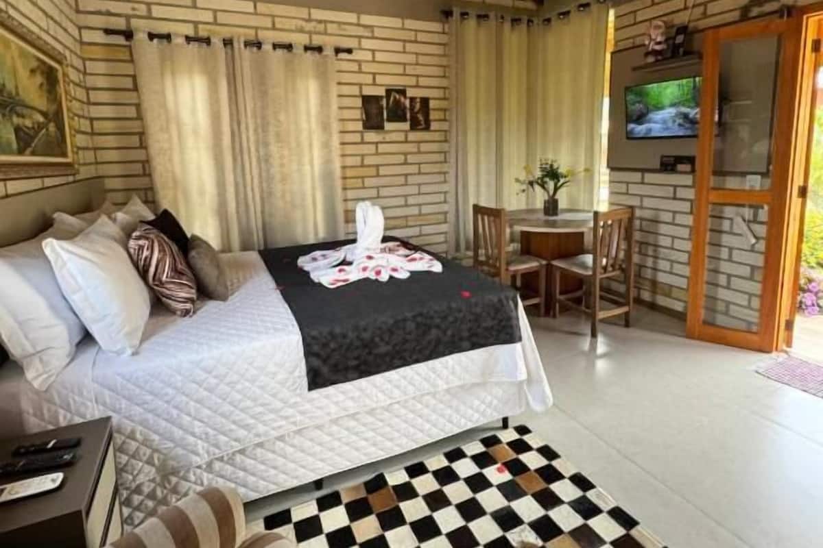 Ein gemütliches Zimmer mit einem Bett, einem karierten Teppich, einem Fernseher und einer Holzbalkendecke.