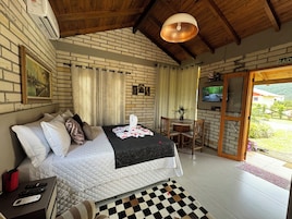 Un dormitorio con cama, escritorio, televisor y vista al exterior.