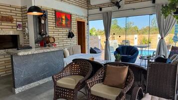 A cozy lounge area with wicker furniture, a fireplace, and a view of the outdoors.