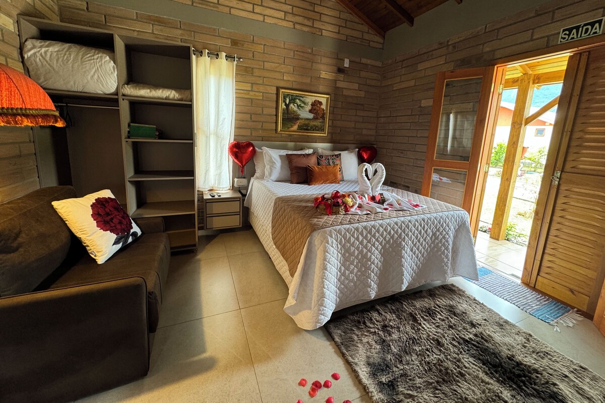 A bedroom with a bed, a nightstand, a wardrobe, a sofa, and a door labeled 'SAÍDA'.