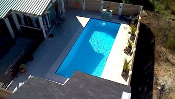 A rectangular swimming pool with a clear blue water surface, surrounded by a paved deck.