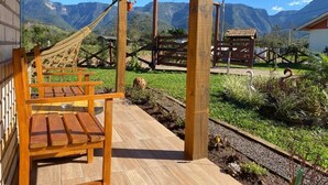 A wooden deck with benches, a hammock, and a view of mountains. - Pousada Mirante dos Canyons (Praia Grande)