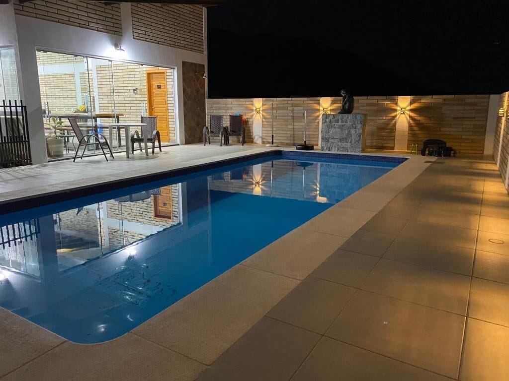 Una piscina interior moderna con agua cristalina, rodeada de un suelo de baldosas y una pared de ladrillo.