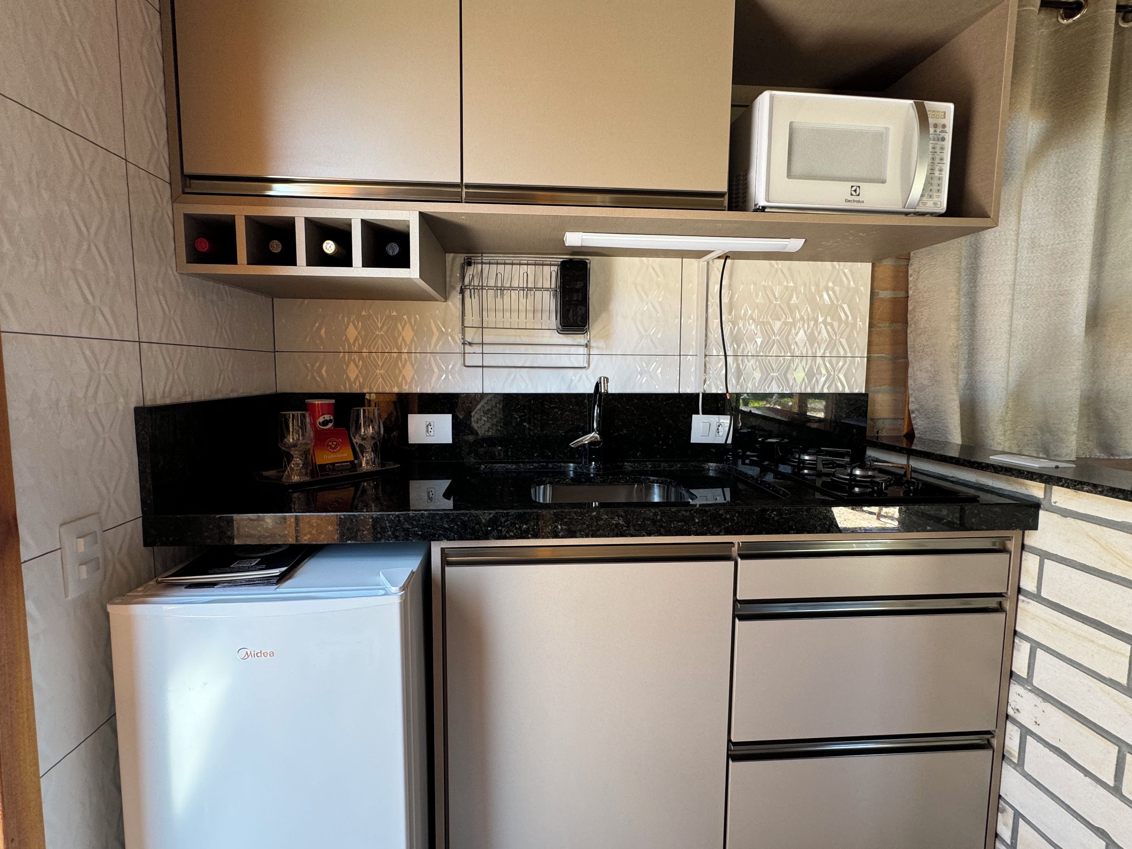 A compact kitchen with a refrigerator, microwave, and stove.