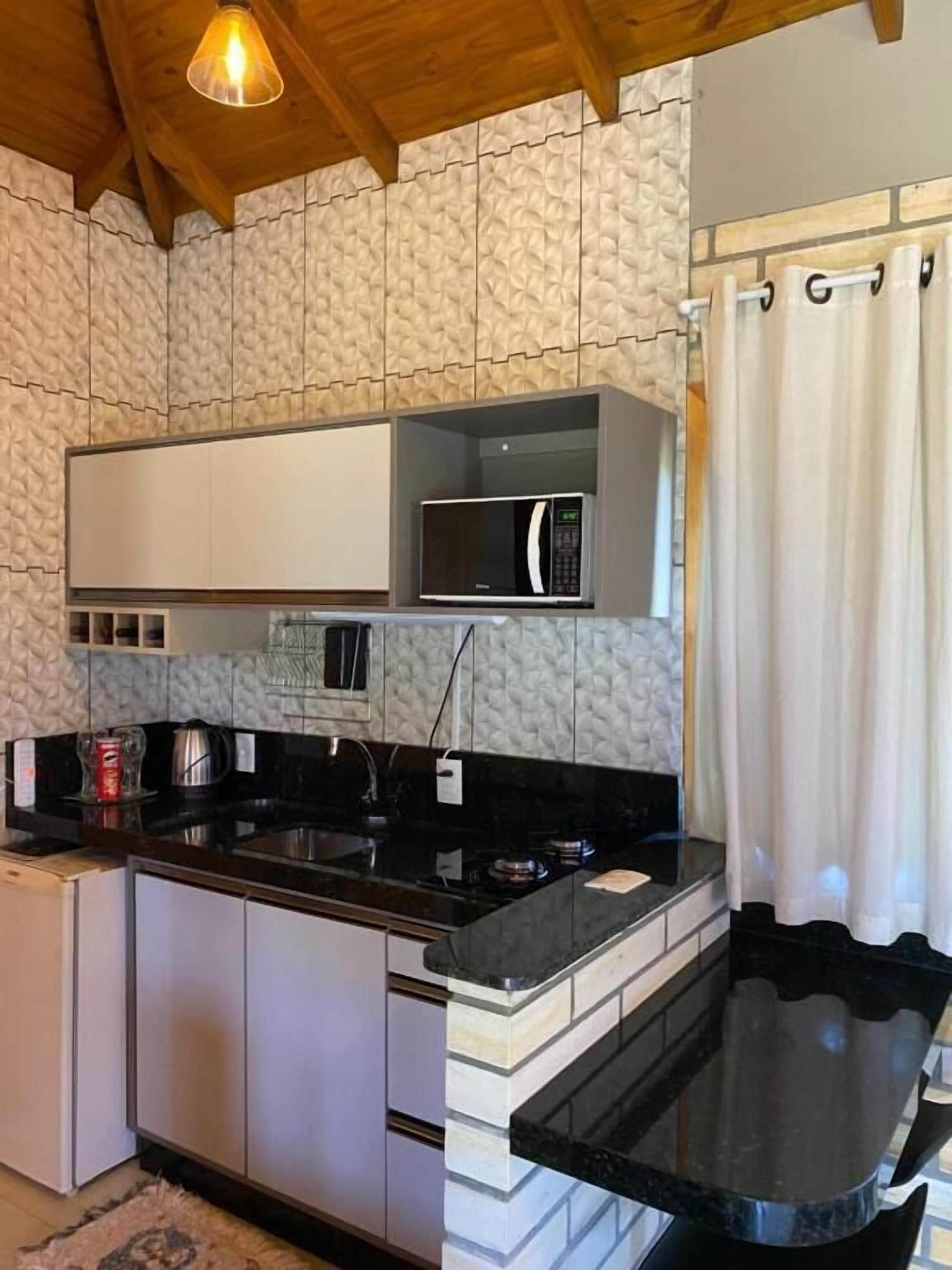 Una cocina compacta equipada con microondas, hervidor y pileta.