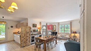 A spacious living area with a dining table, chairs, a sofa, and a kitchen area with cabinets and a refrigerator. - MAISON L'ANGELINE AVEC PISCINE PRIVÉE (Le Plan-de-la-Tour)