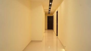 A well-lit, narrow hallway with a shiny floor, leading to a dark door at the end.
