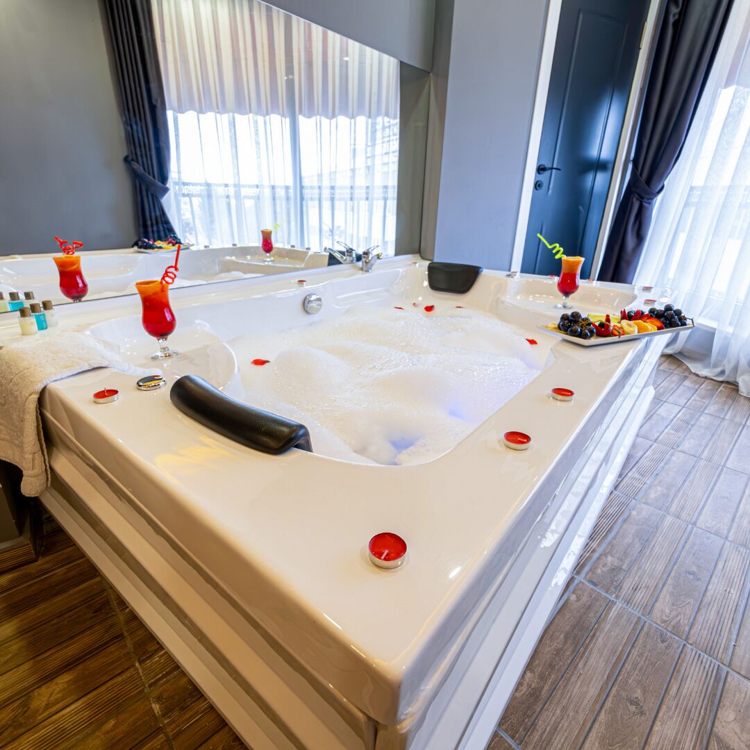 Une salle de bain moderne avec une grande baignoire, un miroir et un plateau de fruits et de collations.