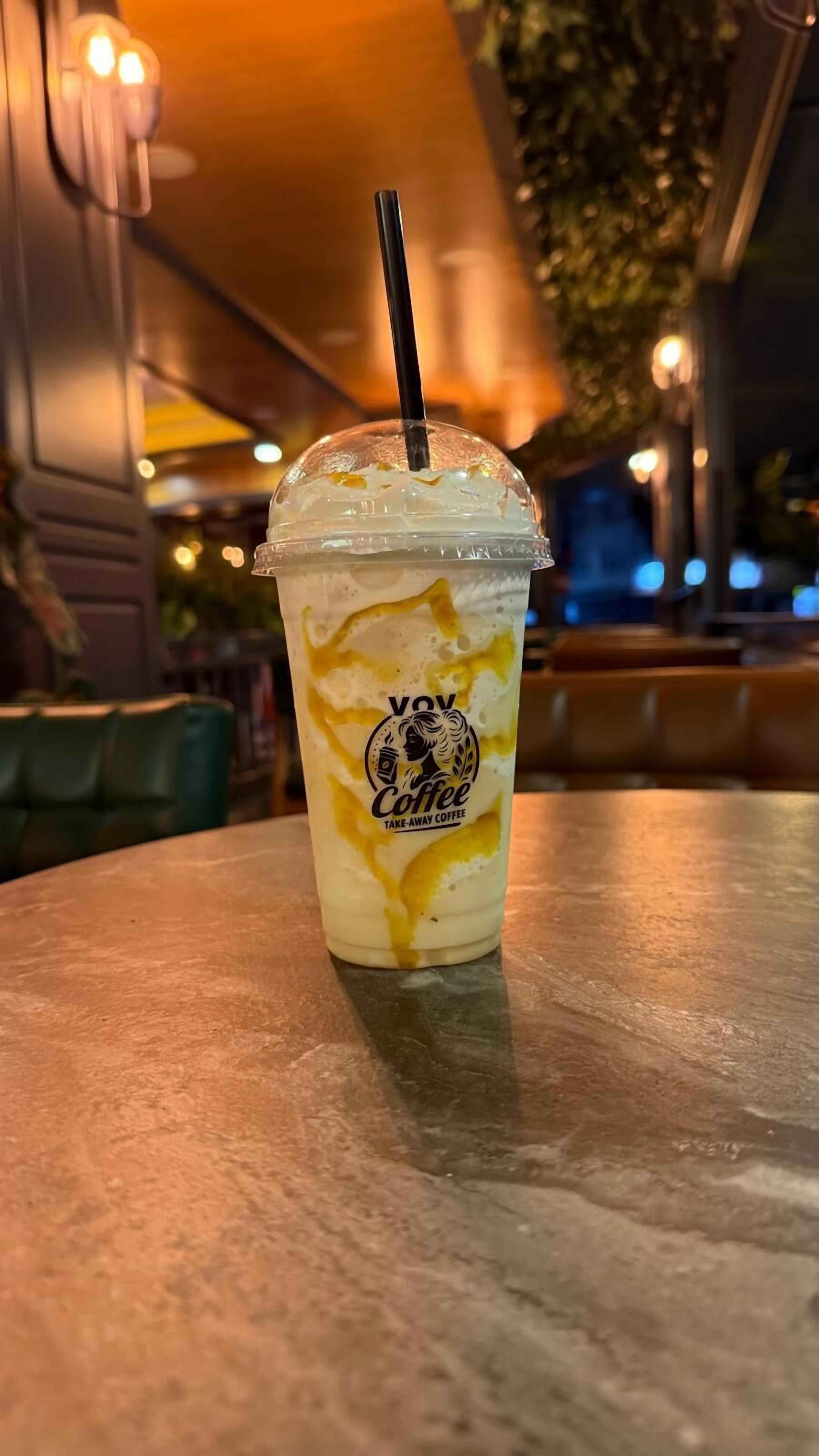 A take-away coffee cup with a straw on a table in a restaurant.