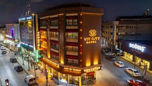 HOTEL VIV CITY con un diseño moderno, situado en una calle concurrida y con señalización visible para un restaurante y una cafetería.