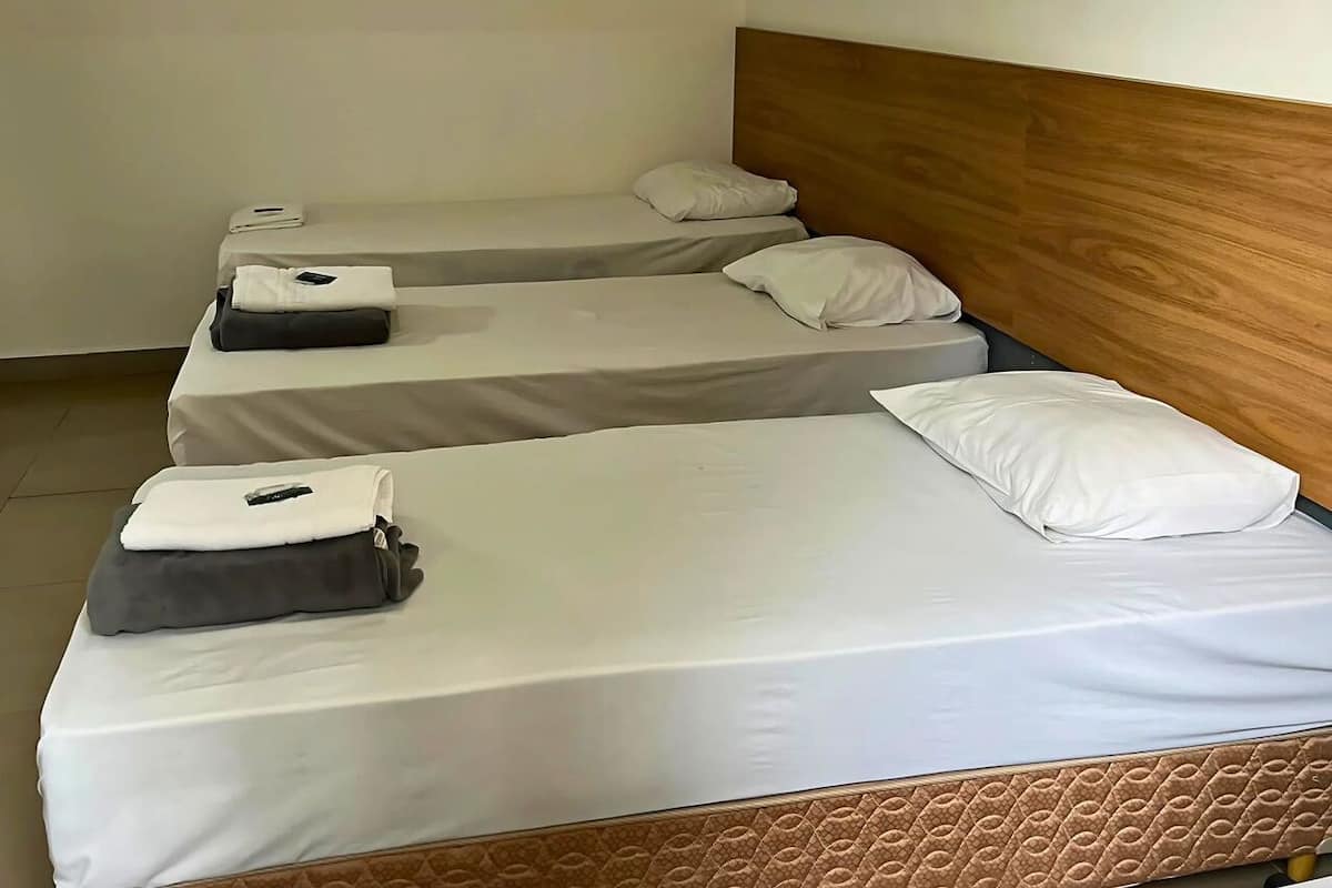 Habitación de hotel con dos camas individuales, cada una con una almohada y un edredón doblado.