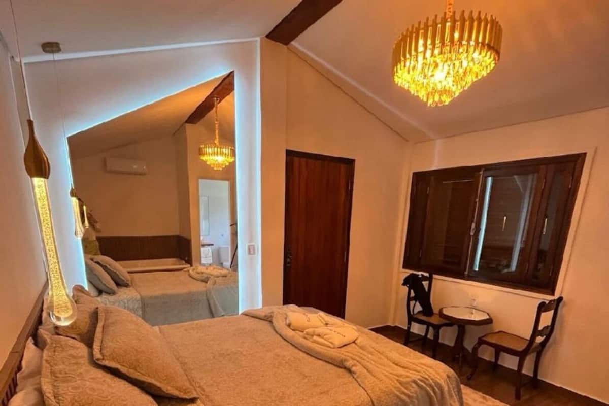 Una habitación de hotel con una cama grande, un escritorio con una silla, una ventana y un candelabro.