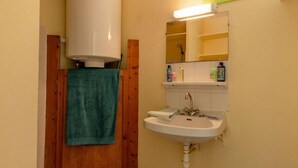 Ein Badezimmer mit einem weißen Waschbecken, einem Spiegel und einem Handtuch, das an einer Holztür hängt.