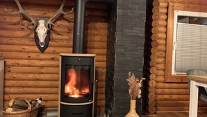 A log cabin interior with a wood-burning stove, a deer skull mounted on the wall, and a basket of firewood. - Nideggen's Schwedenhaus, right next to the forest with great hiking trails and a fireplace. (Nideggen)