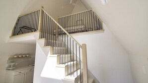 Een meerlaags interieur met een trap, een keukenhoek en een plafondventilator.
