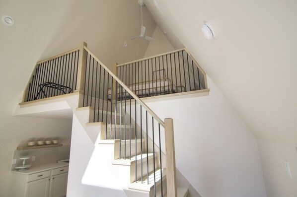A multi-level interior with a staircase, a kitchen area, and a ceiling fan.