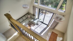 Een moderne woonkamer met een groot raam, een houten trap en een hanglamp.