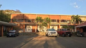 A building with a brick-paved entrance, a white car parked in the center, and a red car on the right. - Bolimar Collection at Playa Hermosa - N4 (Playa Hermosa)