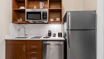 A modern kitchen with wooden cabinets, a stainless steel refrigerator, a microwave, and a dishwasher.