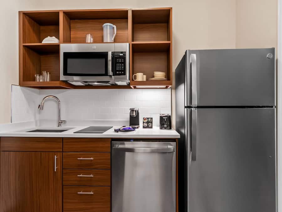 Een moderne keuken met houten kastjes, een roestvrijstalen koelkast, een magnetron en een vaatwasser.