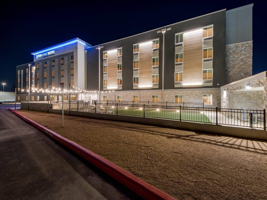 A modern hotel with a sign reading "EVERYHOME SUITES" and a well-lit facade.