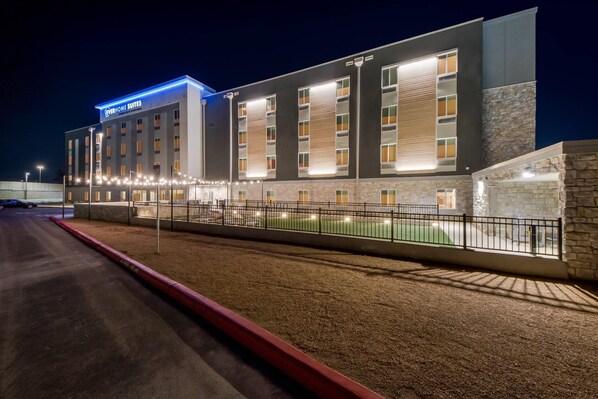 Un hotel moderno con un cartel que dice 'EVERYHOME SUITES' y una fachada bien iluminada.