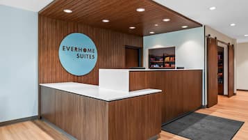 Un mostrador de recepción con detalles de madera y un letrero circular que dice "EVERHOME SUITES".