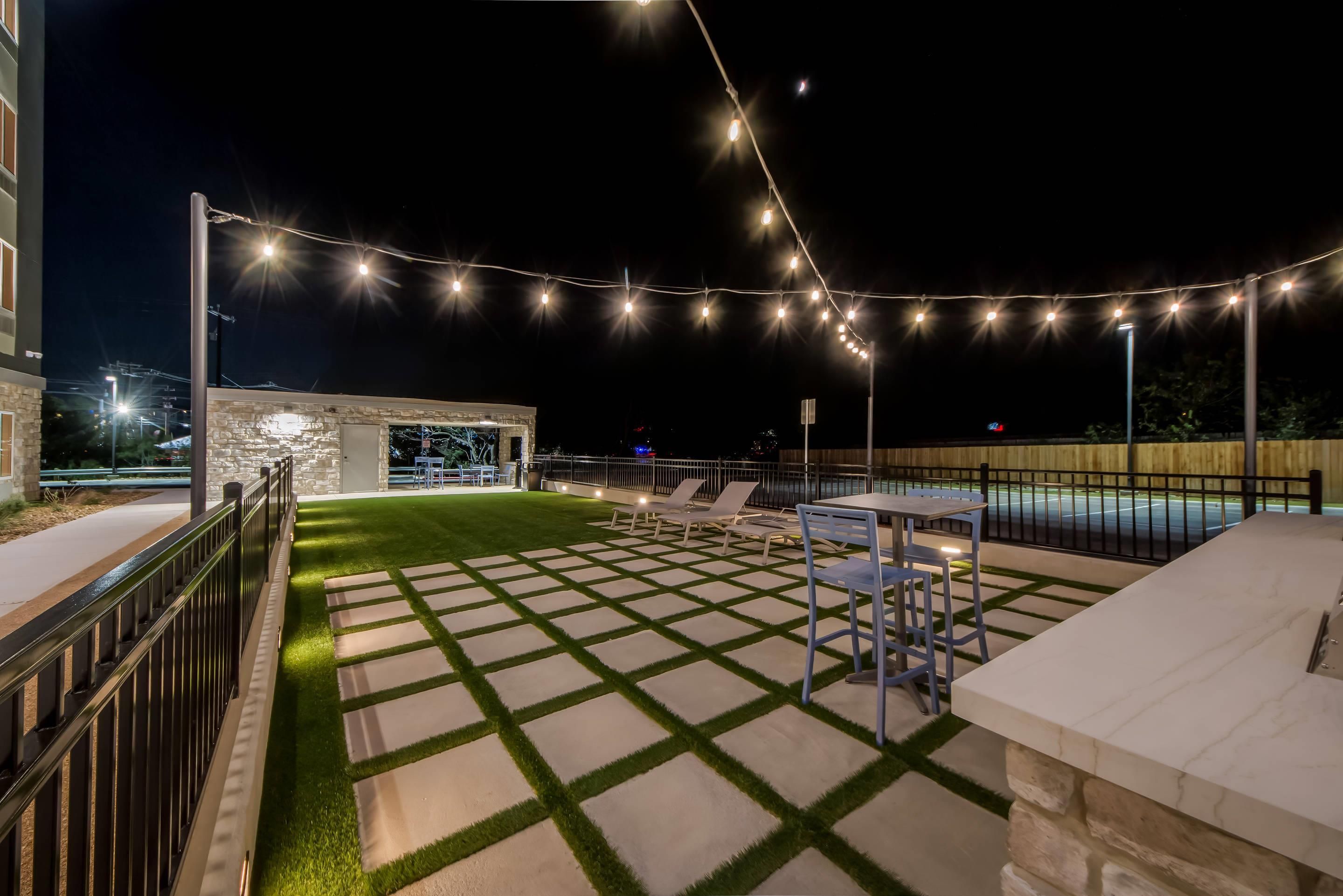 An outdoor patio area with a stone pathway, seating, and string lights.
