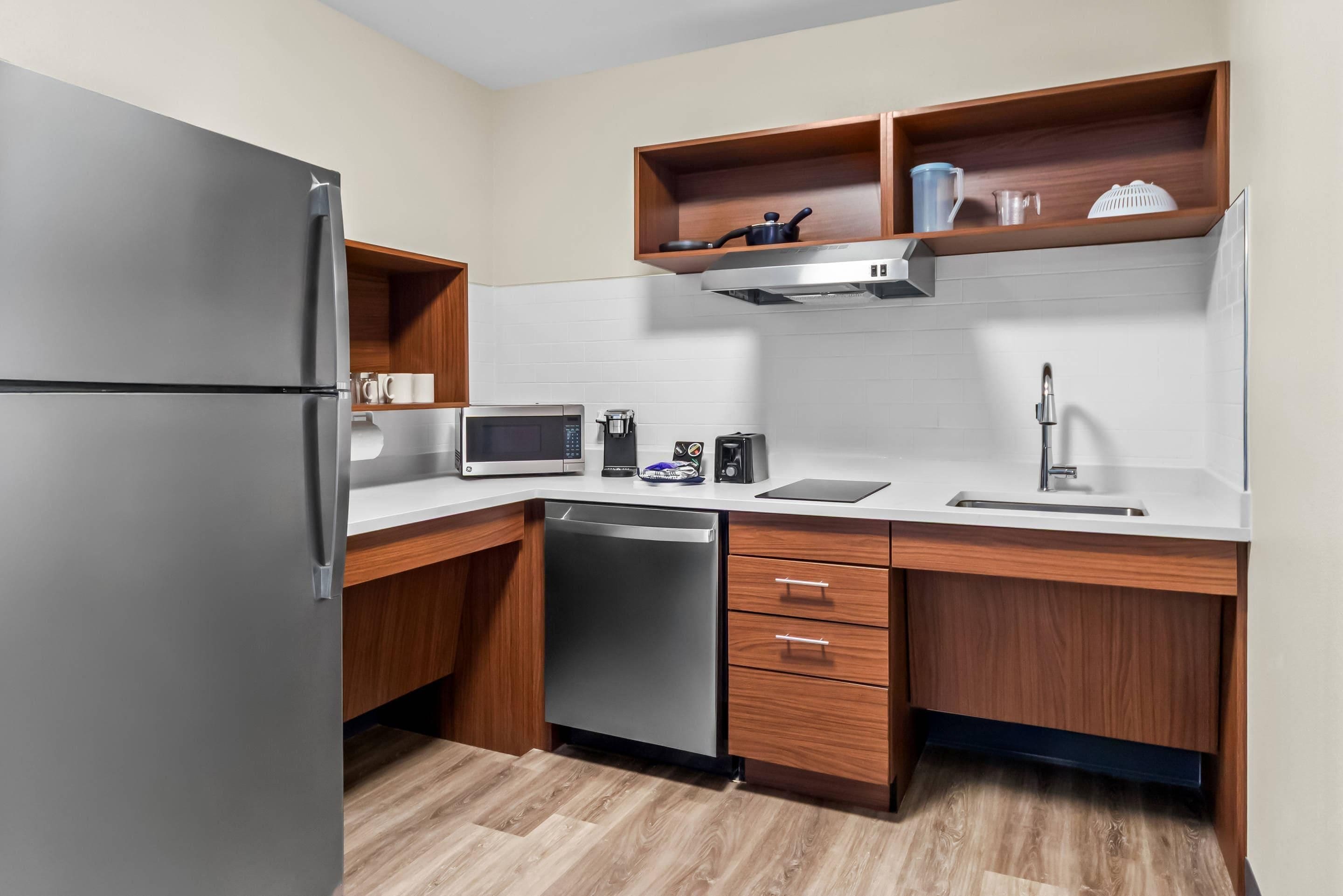 Una cocina compacta equipada con refrigerador, microondas, cafetera y lavavajillas.